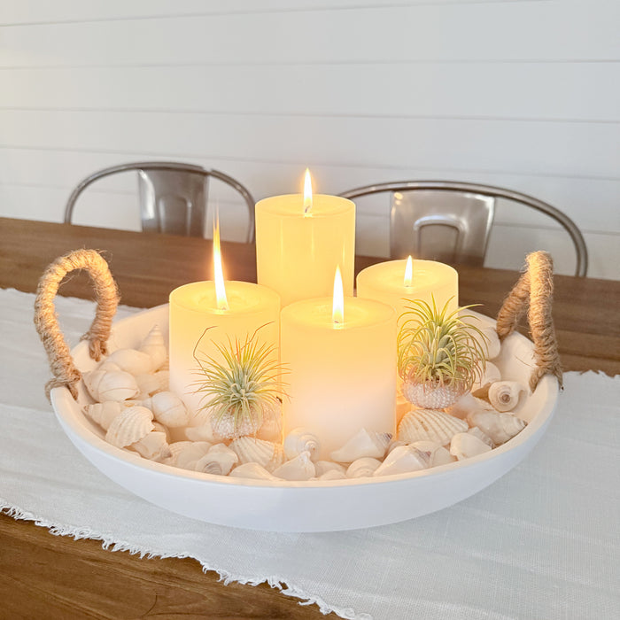 Matte white Ibiza bowl styled with four white pillar candles and white shells. All items sold separately.