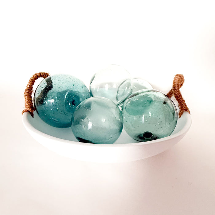White cement bowl with natural jute handles containing four turquoise glass balls. Balls and bowl sold separately.