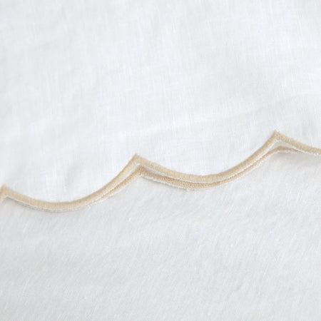 Detail image of the scalloped edge on the Kelly linen sheet set. Scalloped edge embroidered with a flax colored satin stitch on white linen. 100% linen sheet set, includes a fitted sheet, flat sheet and two coordinating pillowcases.