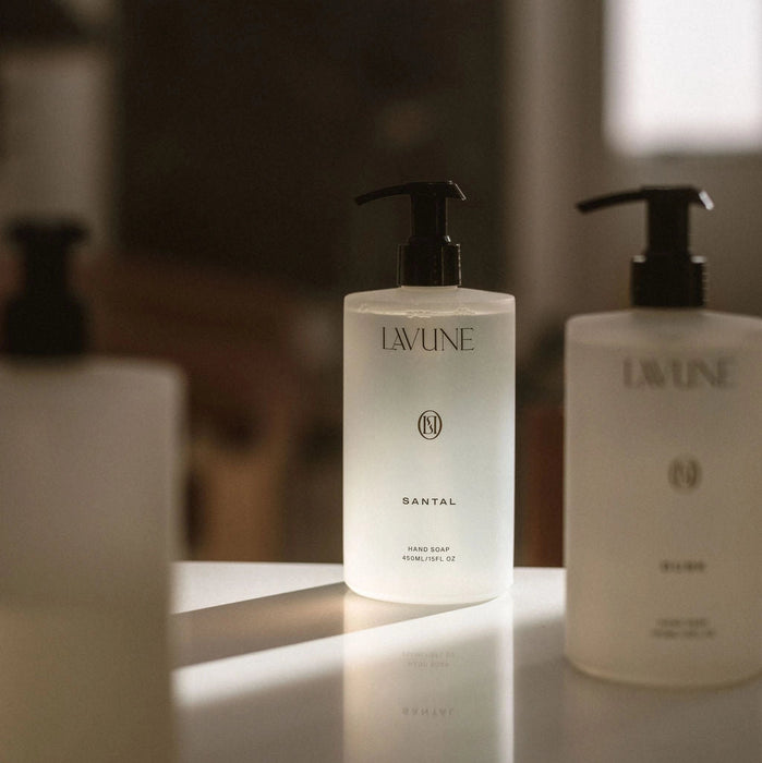 Bottles of LAVUNE Santal  hand soap on a counter with blurred background.