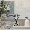 L'AVANT Amber Santal reed diffuser, candle and hand lotion styled on a tray with other decorative objects. Each product sold separately.