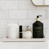 Bathroom tray styled with L'AVANT Fresh LInen hand soap in a black bottle with other toiletries. 