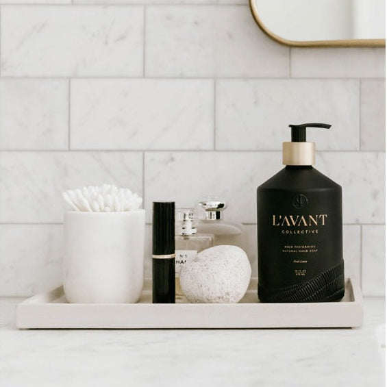 Bathroom tray styled with L'AVANT Fresh LInen hand soap in a black bottle with other toiletries. 
