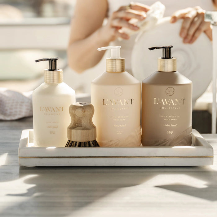 Collection of L'AVANT products in Ambre Santal fragrance on white marble tray. Dish soap, scrub brush, hand wash and hand lotion. Each item sold separately.