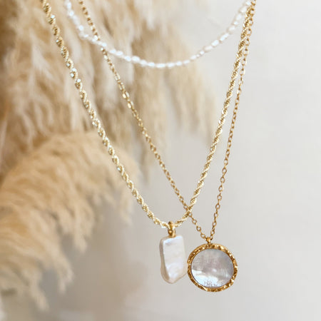 Gold chain with pearl pendant necklace, gold chain with pearl medallion necklace hanging with pampas grass background.