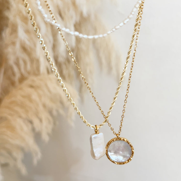 Gold chain with pearl pendant necklace, gold chain with pearl medallion necklace hanging with pampas grass background.