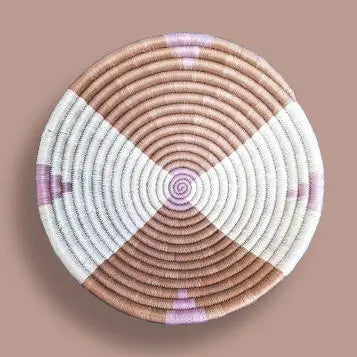 Hand coiled basket bowl made of natural sweetgrass with an abstract pattern of white and lilac on a tan background. 12 inch diameter x 3 inch depth.