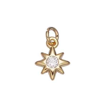 Gold star-shaped charm pendant with a central clear CZ gemstone on white. background. 16K gold plated over brass.