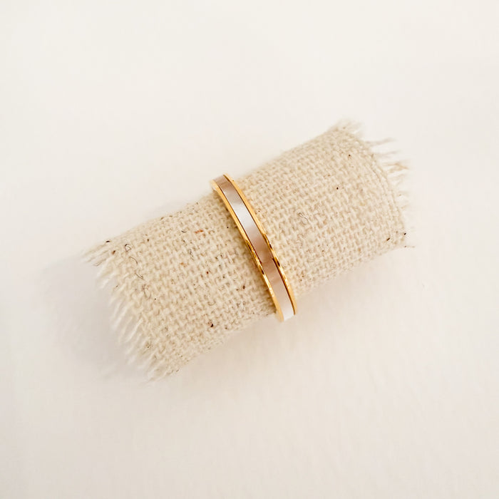 Gold ring band embedded with a band of white Mother of Pearl. Water, sweat and tarnish resistant.