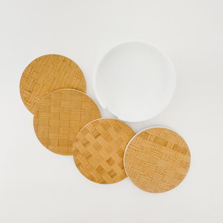 Set of four woven  bamboo coasters with a white resin container on a white surface.
