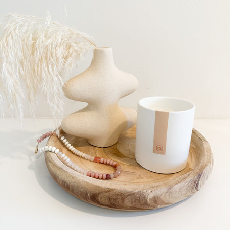 Decorative items styled on a round natural wood tray/shallow bowl on a white surface. All items sold individually.