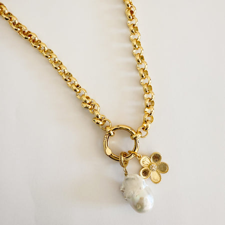 Gold plated chain necklace with a round hinged carabiner encrusted with clear pave' crystals holding a large white baroque pearl pendant and a golden poppy flower pendant. 26 inch length.