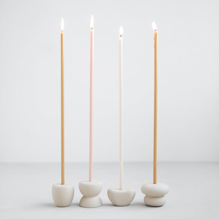 Collection of Pebbles slim taper candle holders. Modern and organic shapes in sand colored ceramic. Designed to fit the slim "Wishing Candles" shown styled in photo-sold separately. Each candle holder sold individually.