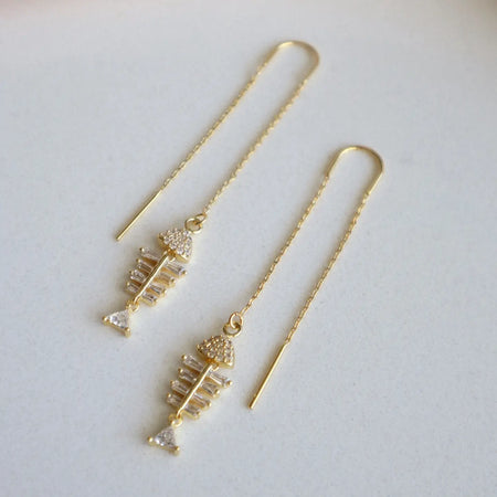 Pair of delicate gold chain threader earrings with a sparkling fishbone charm. 14K gold plated over brass with clear CZ stones. 2 3/8" drop. 