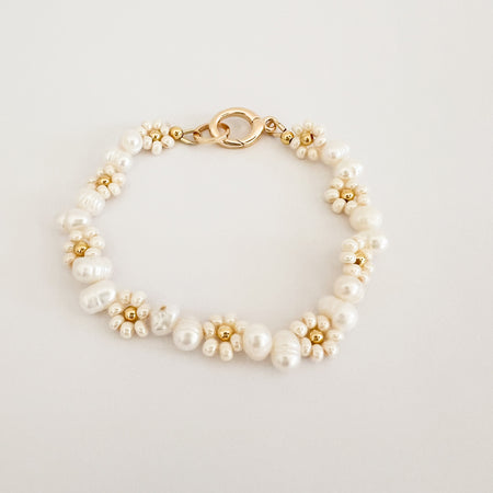 Posies + Pearls bracelets. Hand strung seed pearls in the shape of a daisy with a gold filled ball center. Each daisy is separated by a pair of white Keishi pearls. Hand crafted in Florida. Measures approximately 6" length with gold plated hinge clasp closure.