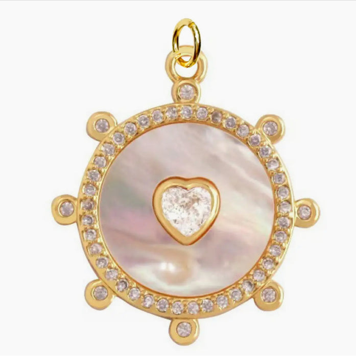 White Mother of Pearl disc charm framed in gold and pave' with a clear CZ heart in the center. 1 inch.