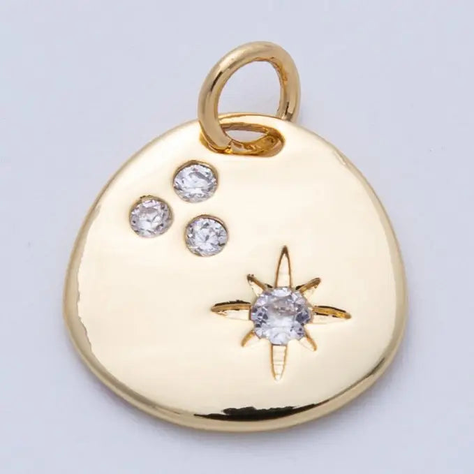 Round gold pendant charm with a shimmering star cluster made of clear CZ stones. 18K gold plated over brass. 14mm diameter.