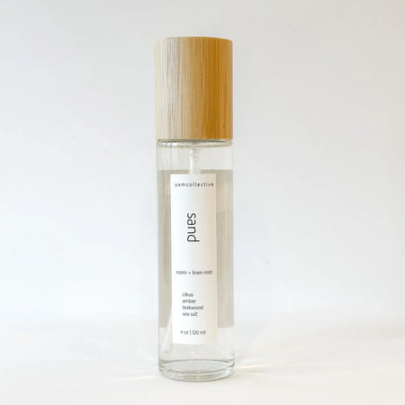 Clear spray bottle with wooden cap containing SAND room and linen mist on white  background. Fragrance notes of Citrus, Amber, Teakwood and Sea Salt. 4 fl oz. 