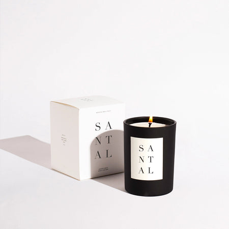 Santal candle by Brooklyn Candle Studio. 100% white soy wax candle fragranced using fine perfume and essential oils. Hand poured into a round matte black glass vessel with an ivory label with elegant black type. Burn time is up to 70 hours, 10 oz. volume. Packaged in a matte ivory box with elegant black typography.