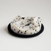 White soap bar with black specks on a black soap dish against a light gray background. White Grapefruit fragrance. 