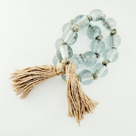 Decorative glass bead garland  in pale blue with natural jute tassels. 34 inch length. 1 inch glass beads.