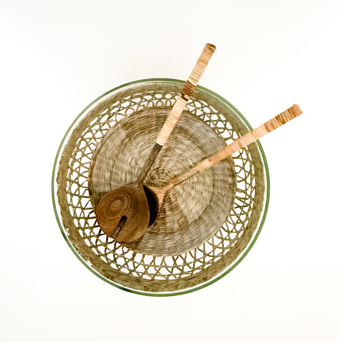 Clear glass serving bowl with a woven natural seagrass cage and wood + rattan salad servers. Each sold separately.