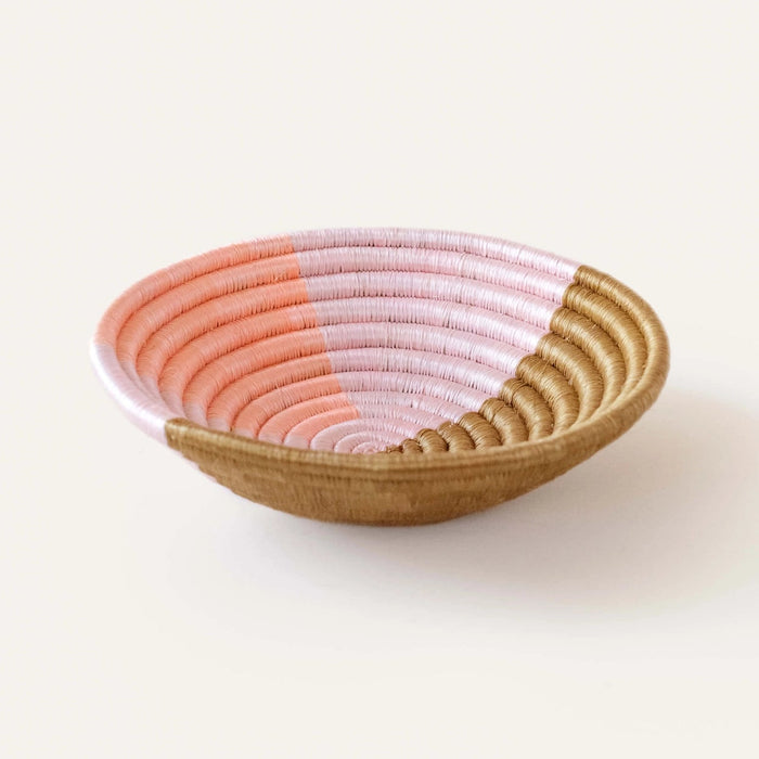 Small basket bowl hand woven in coils of natural sweetgrass with an abstract pattern in pale pink and coral. 8 inch diameter x 2 inch depth.