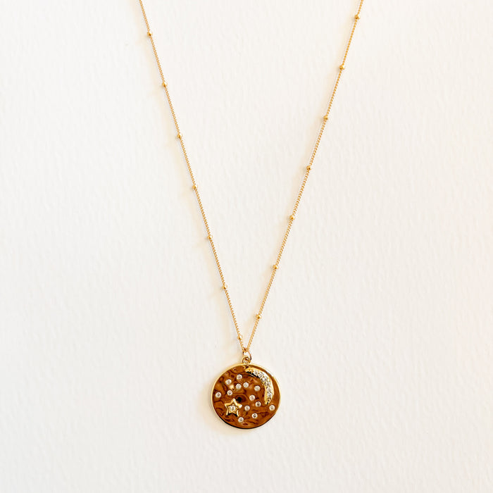 A 14K gold filled satellite chain with a vintage style coin pendant with moon and stars embellished with sparkling Austrian crystals. 18" length.