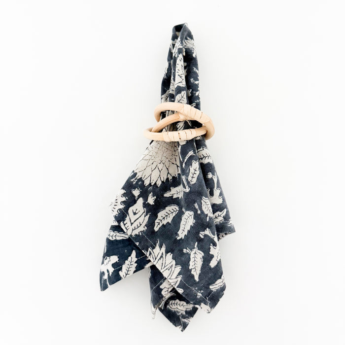 Solstice woodblock print dinner napkin styled with rattan link napkin ring. Each sold separately in sets of 4.