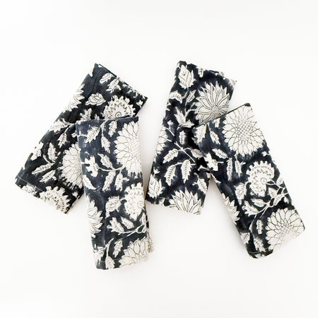 Set of 4 printed cotton dinner napkins folded. Woodblock print in a winter floral pattern in rich indigo and cream. 18 inch square.