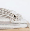 Stack of striped taupe and white towels on a light wooden surface.