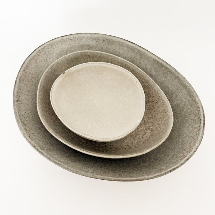 Stack of the Drift stoneware serving bowl, large serving bowl and platter all in an oyster grey glaze. Each piece sold seperatley.