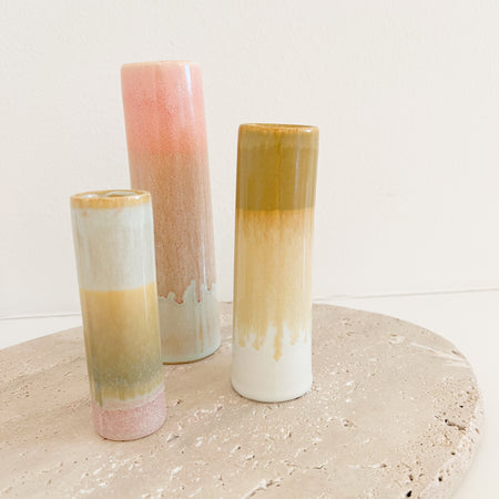 Set of 3 stoneware bud vases. Slim cylindrical bud vases finished in a dripping glaze inspired by the sunset in shades ochre, pink, yellow and white. Measures 4" x 2", 5" x 1.625" x 6.25" x 2".