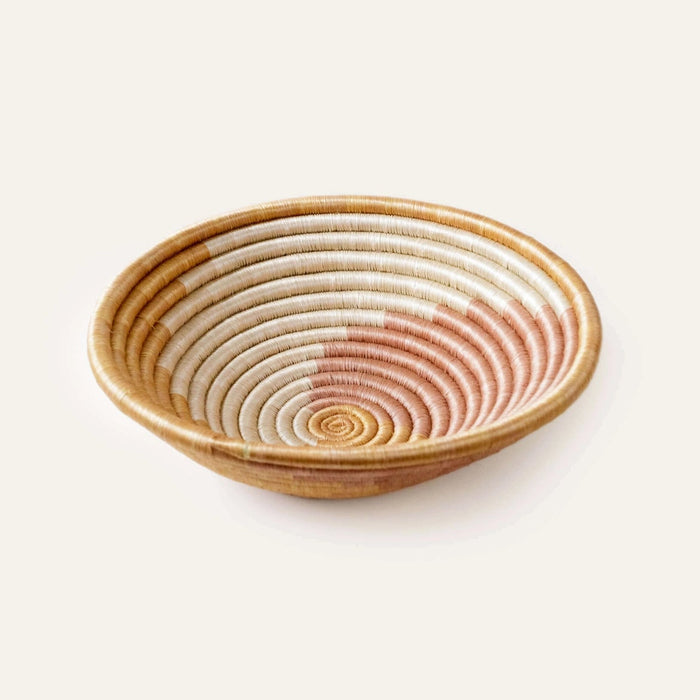Hand coiled basket bowl made of natural sweetgrass with an abstract pattern in ivory and blush pink. 12 inch diameter x 3 inch depth.