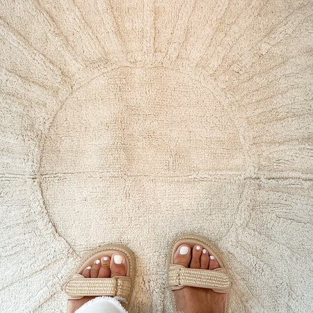 Sunshine Rug. Close up detail of the tufted sunshine design. Soft tufted cream cotton creates the textural sun rays in the center of this rectangular 50" x 30" rug.