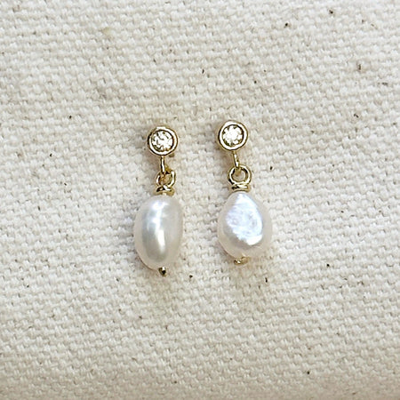 Pair of white pearl drop earrings with a CZ stud and gold fittings on a neutral canvas background. 18K gold filled, with Fresh water Baroque Pearl. 15mm length.