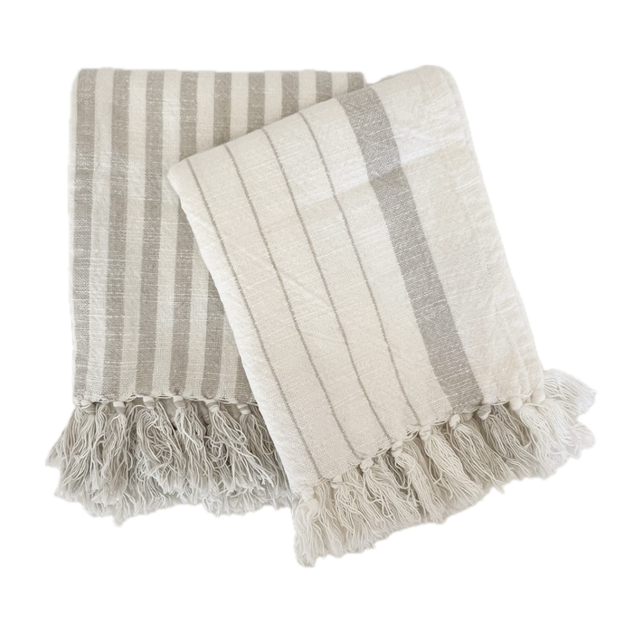 Two styles of the Sydney stripe hand towels. One a classic bengal stripe, the other a fine pinstripe with a thicker stripe border in sand and off white. 100% cotton flat weave hand towel with hand knotted fringe tassels. Each sold separately. 20" x 28"