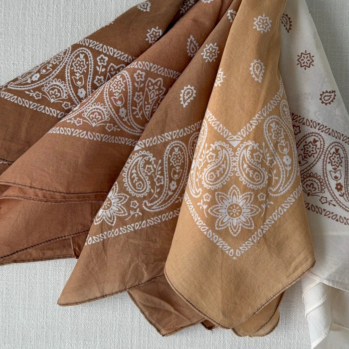 Collection of hand dyed cotton bandanas in shades of terra cotta and cream. Each piece will vary. 