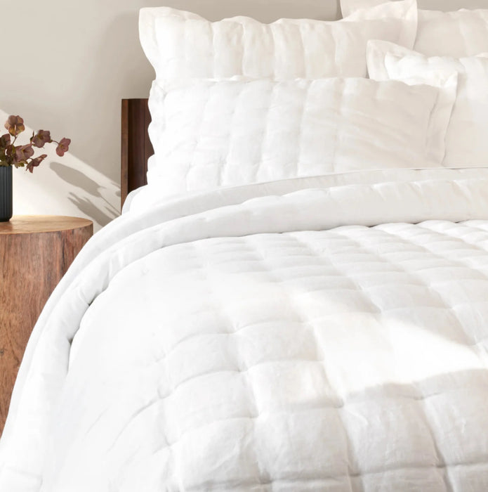 Bed made up in the white luxe linen quilt and shams by Annie Selke. All items sold separately. Quilt has 100% linen face with the reverse in a soft silky rayon. Lightly padded and quilted in a modern box pattern. Quilt available in Full/Queen 102 x 95 inches and 118 x 95 inches.