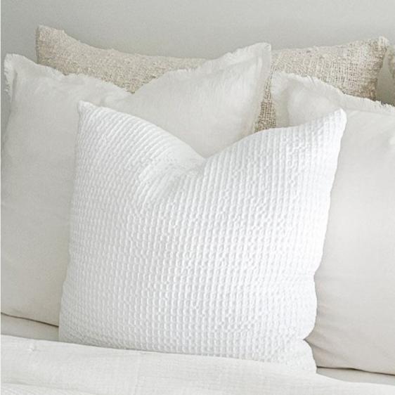 White waffle euro pillow styled with linen and boucle pillows in shades of white and cream. All sold separately. White waffle pillow is made of 100% cotton with a luxe down insert. Measures 26" x 26".