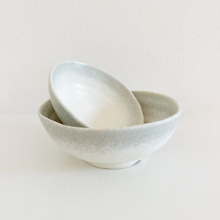 Small and medium Shoreline bowls. Two ceramic bowls in a creamy white glaze with a soft grey border. Each sold separately. Small 4" diameter, 1.5" height. Medium: 5" diameter, 2" height.