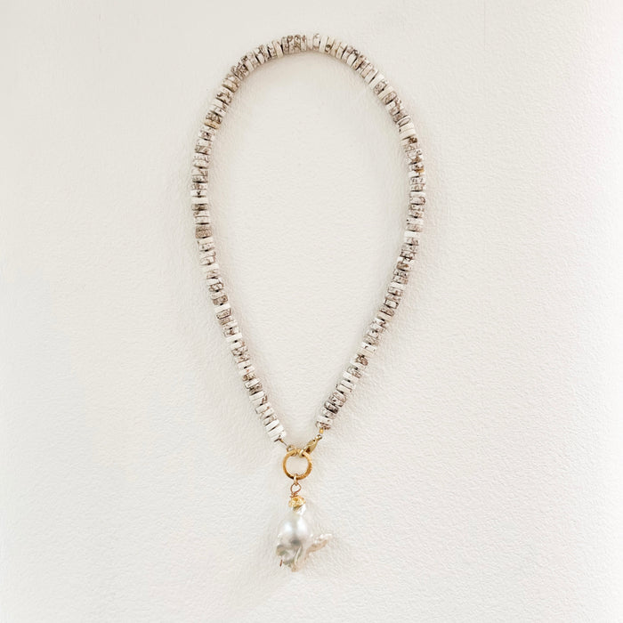 Surfer Glam necklace made from natural shell heishi beads with a large white baroque pearl pendant suspended from a gold ring. 18" length. Hand crafted by Bittersweet Designs in New Mexico.
