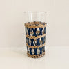 Tall Newport Cane Tumbler. Tall clear glass tumbler wrapped in handwoven lattice work in a combination of natural and indigo dyed cane. Measures 6" height 3" diameter. Glass is removes from cane sleeve for easy cleaning.