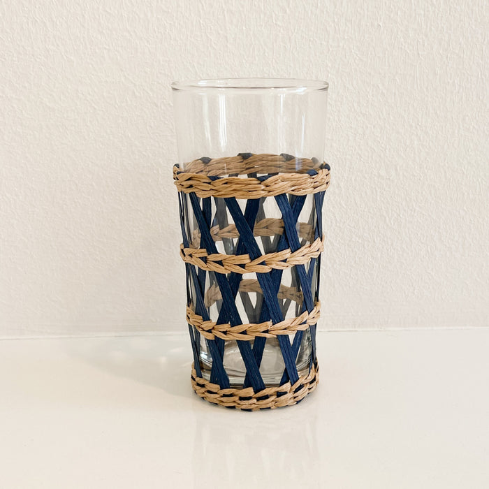 Tall Newport Cane Tumbler. Tall clear glass tumbler wrapped in handwoven lattice work in a combination of natural and indigo dyed cane. Measures 6" height 3" diameter. Glass is removes from cane sleeve for easy cleaning.