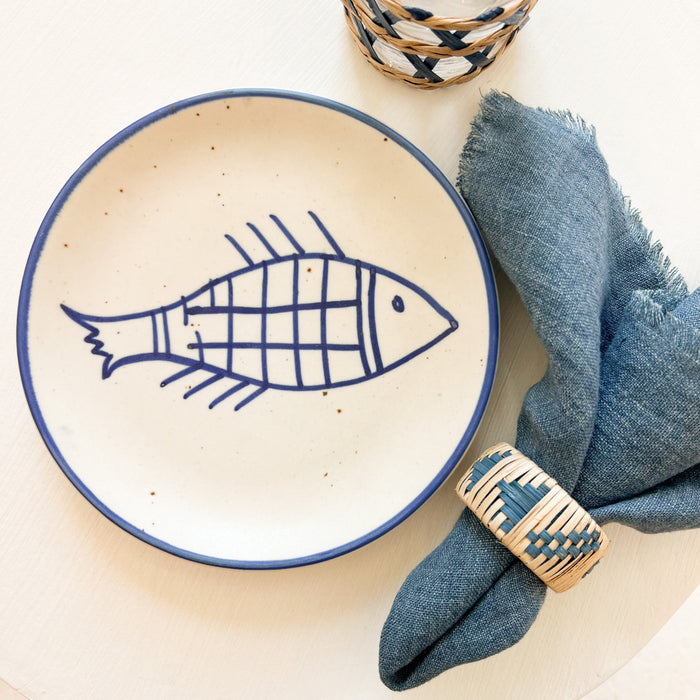 Pisces Stoneware Plate shown with indigo linen cocktail napkin and Akumal cane napkin ring. Each sold separately. Perfect for tapas or serving small bites.