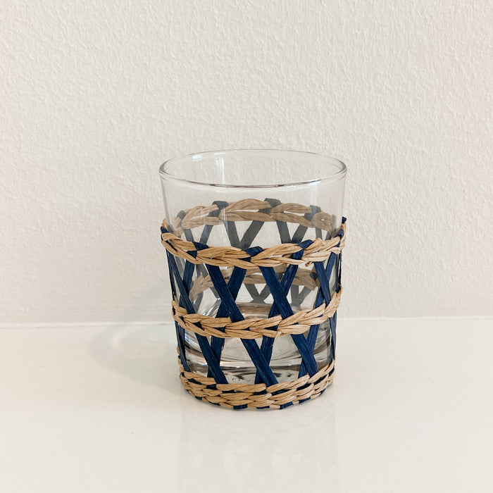Short Newport Cane Tumbler. Clear glass tumbler wrapped in hand woven  lattice work in a combination of natural and indigo dyed cane. Measures 3.75" height 3" diameter. Glass removes from sleeve for easy washing.