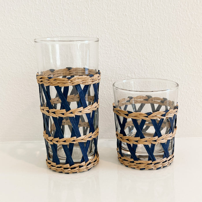 Short and tall Newport cane tumblers. Clear glass tumblers wrapped in a handwoven lattice sleeve in natural and indigo dyed cane. Each sold separately.
