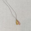 Pink coral and gold tag charm necklace, strung on grey silk cord.