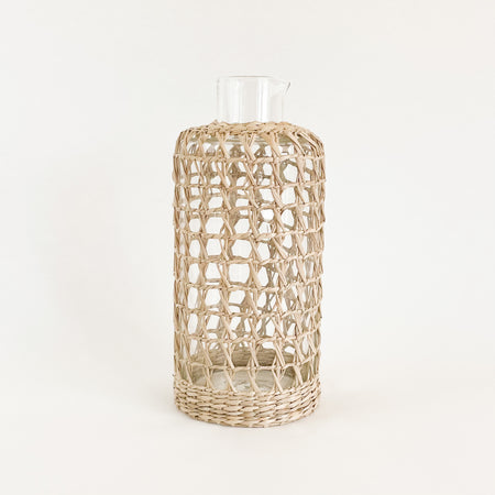 Seagrass cage carafe is perfect for the natural bohemian table. Made from recycled glass and wrapped in a hand woven seagrass cage. Measures 9" H 4" D at base.