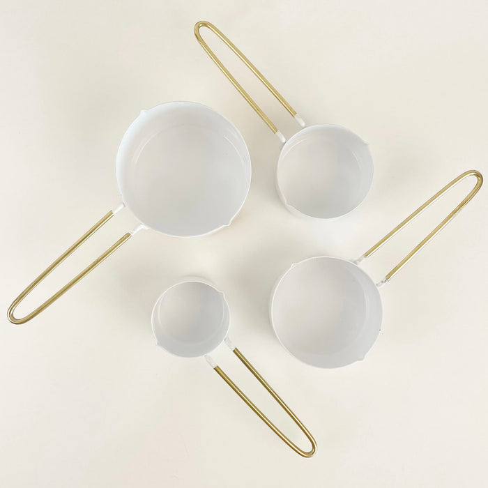 Set of 4 white enamel measuring cups with a brass finished hairpin handle. Set of 4 includes 1 c, 1/2 c/ 1/3 c and 1/4c. A bright and stylish essential for the modern kitchen.